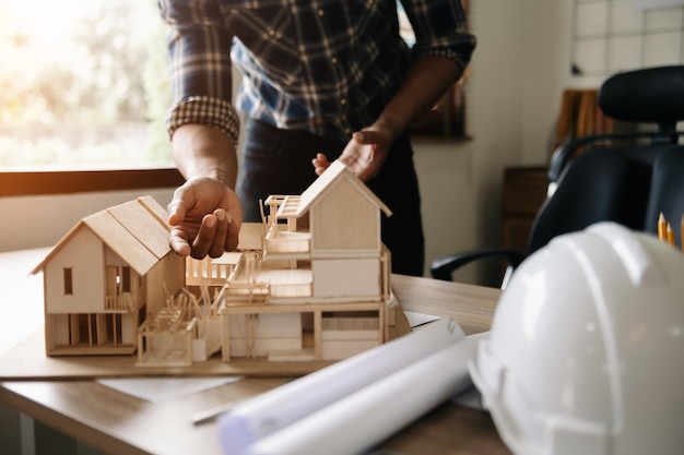 Schot van schaalmodelhuis op tafel met architecten Twee architecten maken samen een architectonisch model in kantoor om een nieuw gebouw te vormen