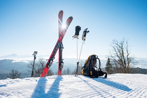 Foto schot van ski-uitrusting - ski's, rugzak, stokken, handschoenen en actiecamera op monopod