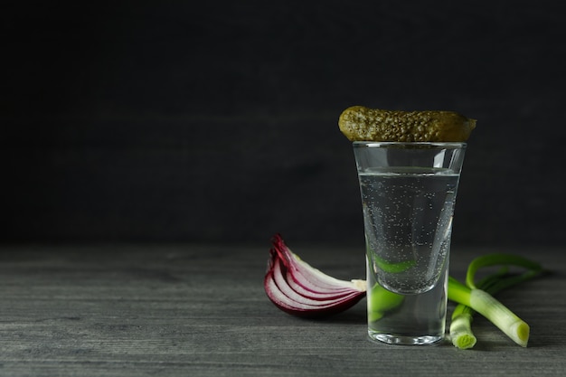 Schot van wodka met augurk en ui op grijze tafel