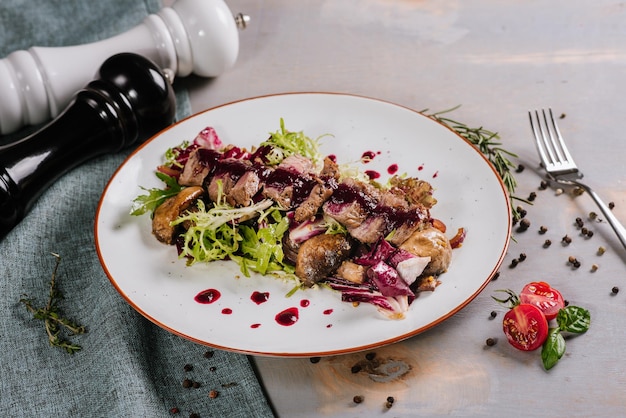 Schotel met eendenvlees met saus en kruiden op de houten achtergrond