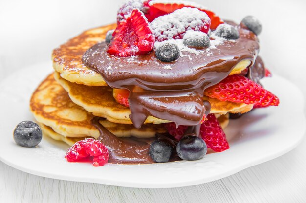 Schotel met pannenkoeken en aardbei, framboos en bosbes en chocolade