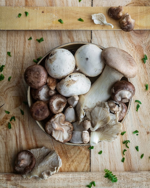 Foto schotel met verschillende rauwe champignons op houten tafel.