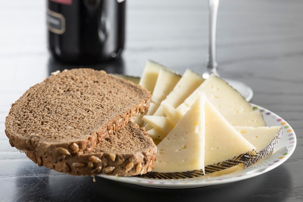 Schotel van gezouten kaas met roggebrood op de achtergrond het lijkt op een glas en een fles wijn