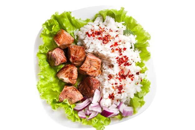 Schotel van rijst, gebakken vlees en groene salade met kruiden. Het is geïsoleerd