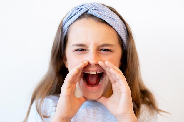 Schreeuwend kinderportret. Aandacht zoekend gedrag. Communicatie probleem. Gekke angstige meisje schreeuwen met holle handen rond open mond verhogen stem geïsoleerd op een witte achtergrond.