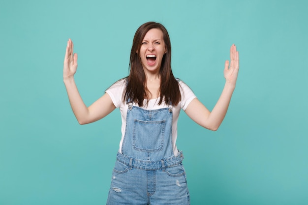 Schreeuwende jonge brunette vrouw meisje in casual denim kleding geïsoleerd op blauwe turkooizen achtergrond. Mensen levensstijl concept. Bespotten kopie ruimte. Gebaren demonstreren grootte met horizontale werkruimte.