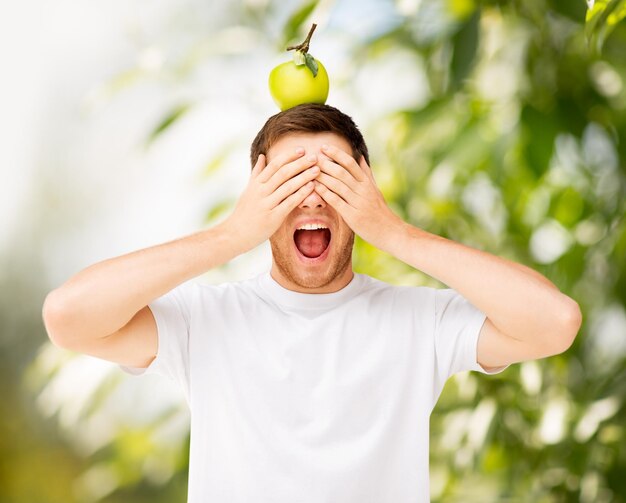 Schreeuwende jonge man met groene appel op zijn hoofd