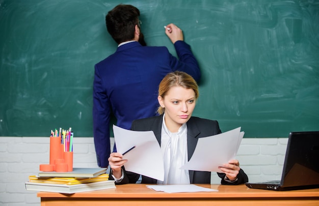 Schrijf je taak op. Leraren die in de klas van de parenschool werken. School opvoeder en leraar stagiair met documenten. Educatief programma. Schoolonderwijs. Bereid je voor op schoolles. Huiswerk controleren.