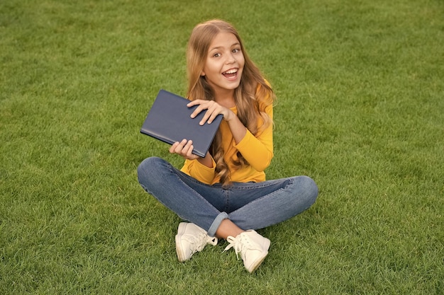 Schrijf jeugdherinneringen kind lees boek in park gelukkig klein meisje studie op vakantie kind schoonheid mode tiener meisje geïnspireerd met nieuw boek ontspannen op groen gras lente vrije tijd gelukkige jeugd