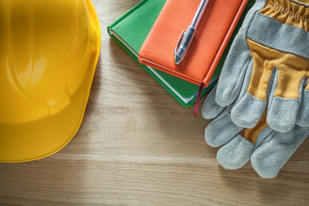 Schrijfblokken pen beschermende handschoenen veiligheidshelm op houten bord