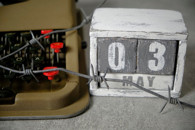 Schrijfmachine is omwikkeld met prikkeldraad met houten kalender naast de datum 3 mei Concept Persvrijheidsdag