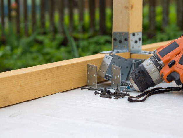 Schroevendraaier zelftappende schroeven en metalen hoeken op de werkplek het concept van het monteren van een houten huis
