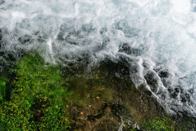 Schuimend helder water en groene algen op de bodem