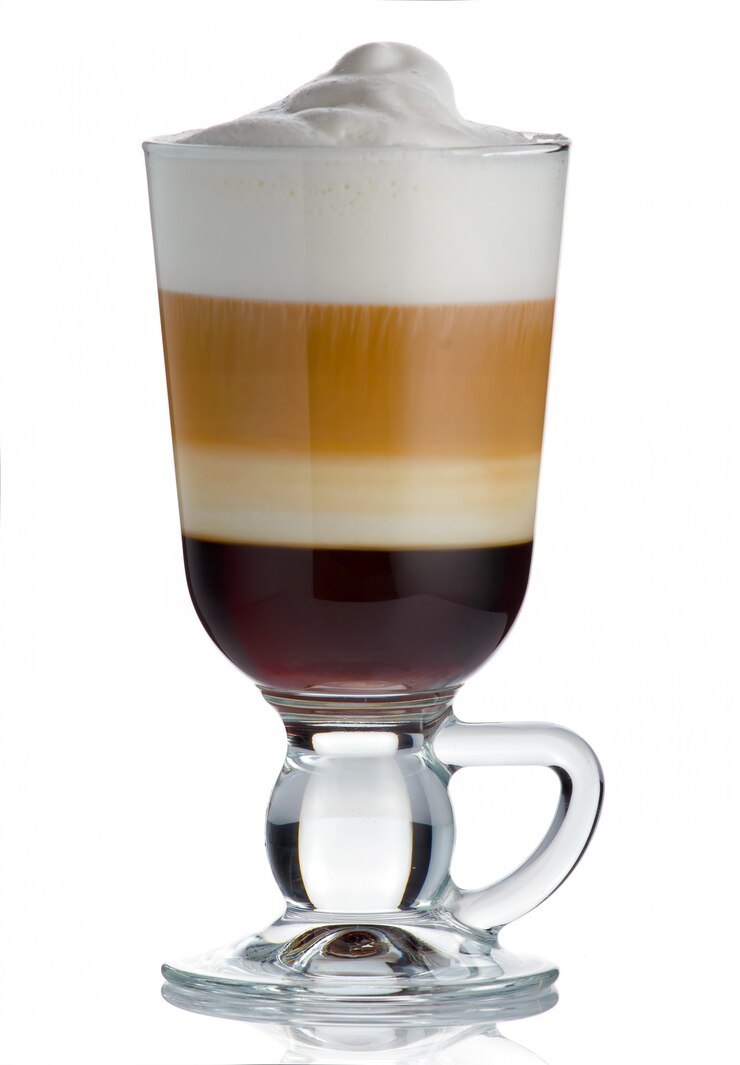 Schuimige, gelaagde cappuccino in een mok van helder glas met kaneel bestrooid