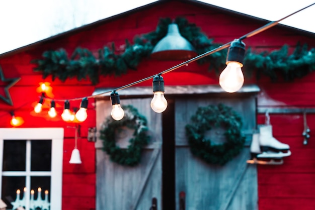 Schuur van het huis versierd voor Kerstmis met gloeilampen kransen schaatsen en slingers