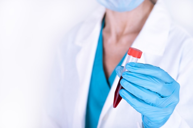 Science, chemistry, biology, medicine and people concept - close up of young female scientist holding test tube with blood sample making research in clinical laboratory