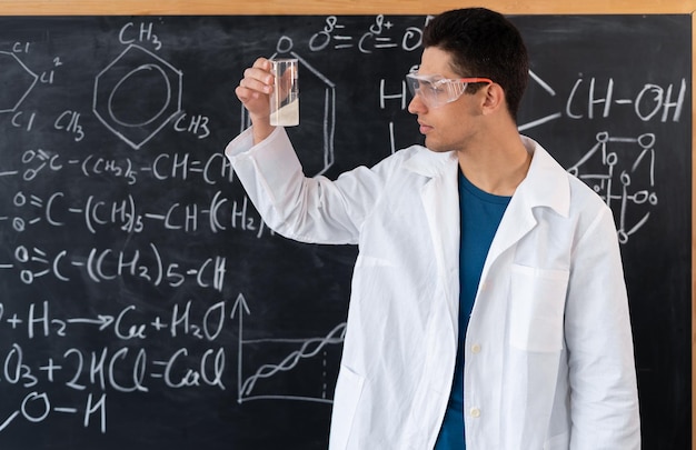 Наука химия университетский ассистент лаборатории делает химический эксперимент с жидкостями в колбе молодой арабский студент делает эксперимент смешивания кислоты университетское образование