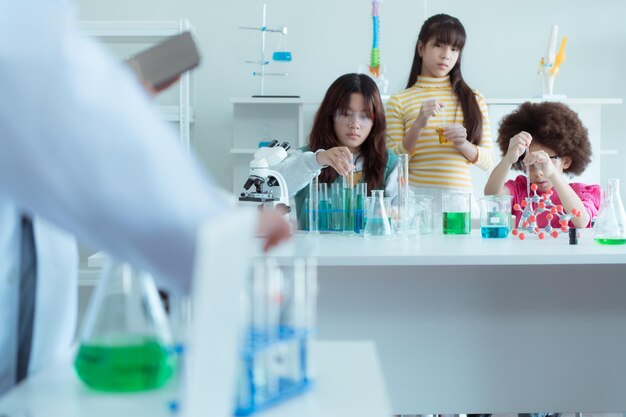 Foto in classe di scienze un bambino scienziato asiatico sta sperimentando formule scientifiche