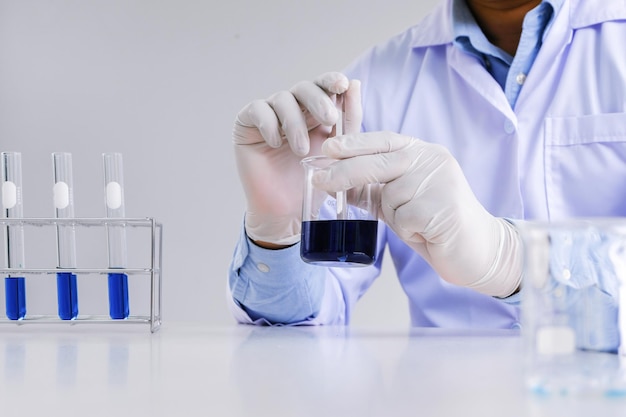 Science innovative Male medical or scientific laboratory researcher performs tests with blue liquid in laboratory equipment science experiments technology Coronavirus Covid19 vaccine research