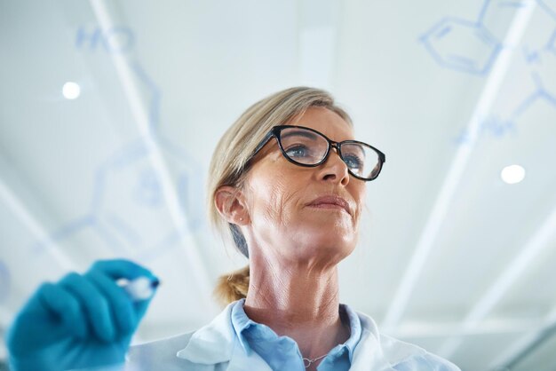 Science is one of the most important channels of knowledge Shot of a mature scientist drawing molecular structures on a glass wall in a lab