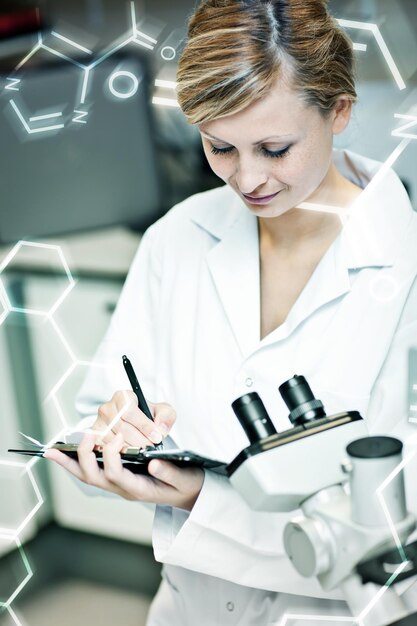 Science and medical graphic against concentrated female scientist writing on her clipboard
