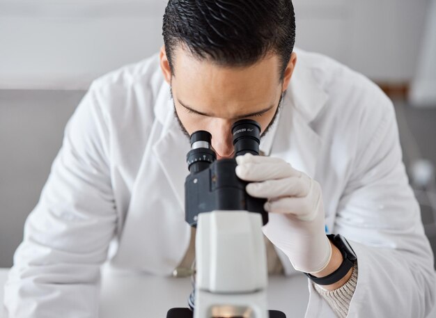 Science microscope and a doctor man at work in a laboratory for innovation or research Medical analytics and biotechnology with a male scientist working in a lab for breakthrough