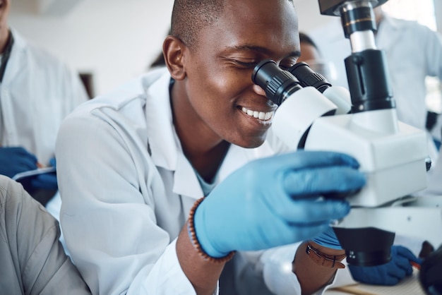 Научный микроскоп и студенты, изучающие физику в классе и довольные исследованиями в лаборатории Ученый-новатор и африканский подросток в старшей школе, изучающий микробиологию для образования