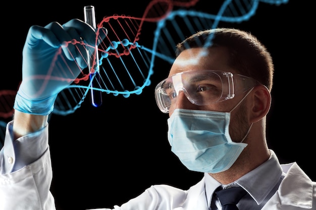 Foto concetto di scienza, ricerca e genetica: giovane scienziato con occhiali di sicurezza, maschera facciale con provetta e proiezione virtuale della molecola di dna