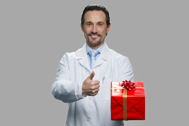 Science researcher showing gift box and thumb up. Holiday celebration concept.