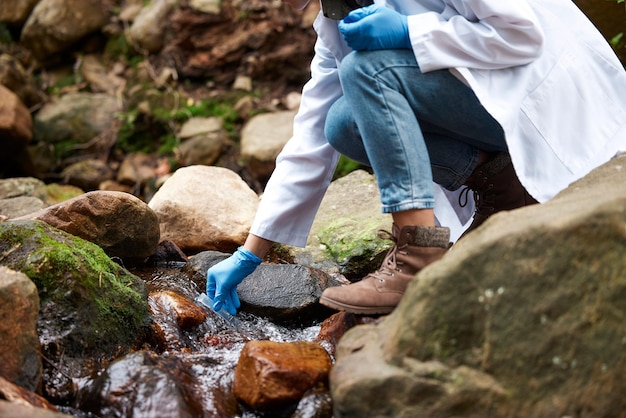 科学の川と環境検査チェックとサンプルのための水の試験管を持つ女性持続可能な農業と分析研究と研究のための森の女性科学者の手