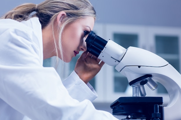 Foto studente di scienze che osserva tramite il microscopio in laboratorio