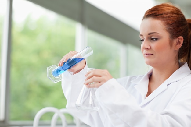 Photo science student pouring liquid in an erlenmeyer flask