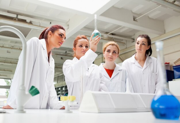 Foto studenti di scienze che guardano un liquido in un pallone