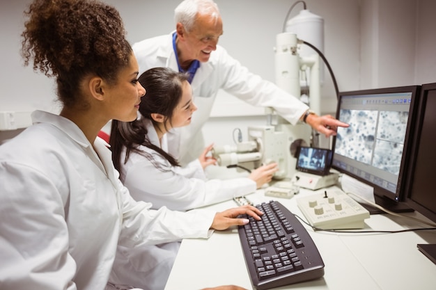 Science students looking at microscopic image on computer with lecturer