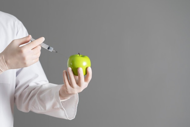 Un lavoratore scientifico con la siringa fa un'iniezione nel frutto crudo