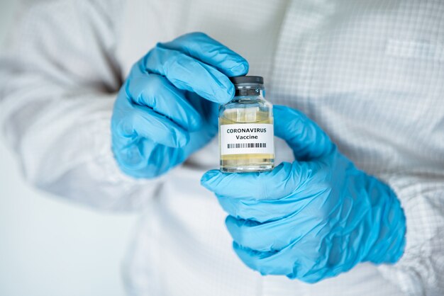 Scientific with protective suit holds a vaccine for coronavirus.