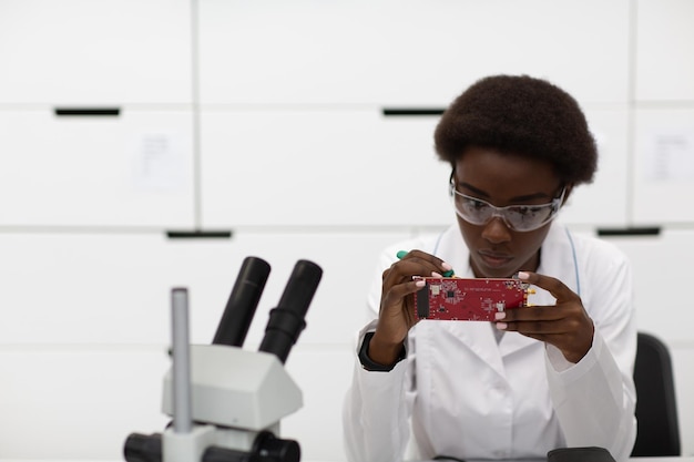 Ученый афро-американских женщина, работающая в лаборатории с электронными приборами
