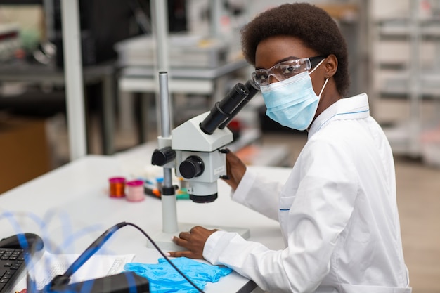 Scientist african american woman working in laboratory with electronic tech instruments and microscope research and development of electronic devices by color black woman