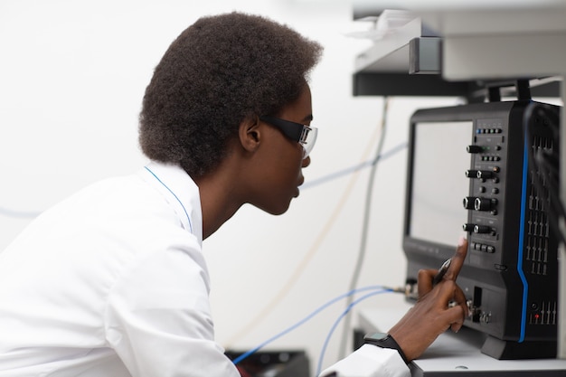 Scientist african american woman working in laboratory with\
oscillograph electronic tech. research and development of\
electronic devices by color black woman.