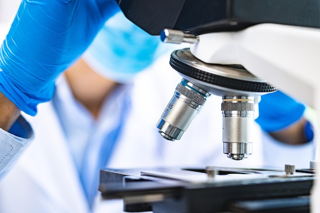 Scientist analyzing microscope slide at laboratory Young woman technician is examining a histological sample a biopsy in the laboratory of cancer research