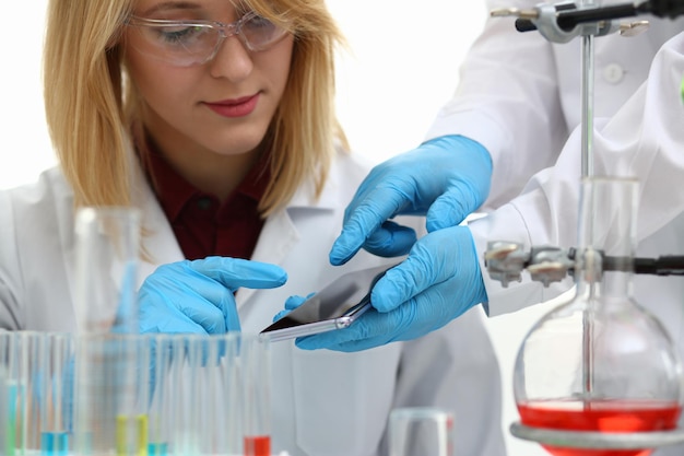 Scientist in chemical laboratory holds smartphone with a display in hand