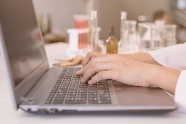 Mano di scienziato o medico digitando sulla tastiera del notebook portatile per il risultato del test.