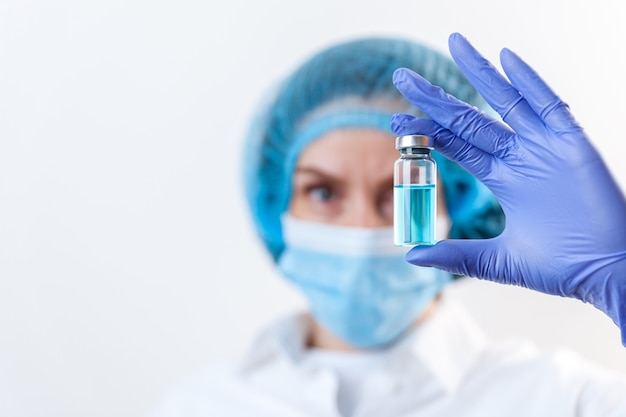 Scientist doctor woman in protective gloves, mask holding injection vaccine, medication