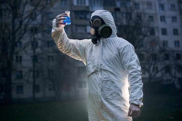 Scientist doing research outdoors wearing white coverall and gas mask