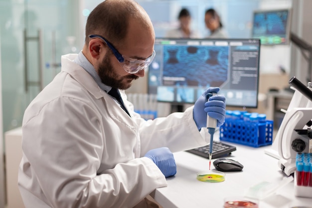 Scientist dropping blood sample with micropipette on petri dish