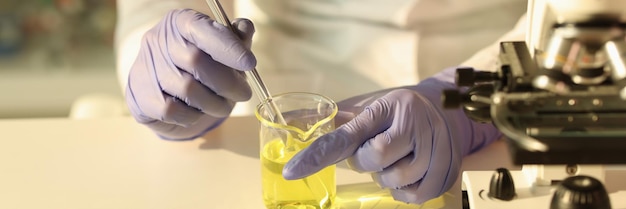 The scientist hands in gloves with a pipette in a yellow liquid closeup fuel testing expertise