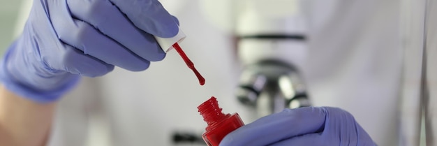 빨간색 페인트를 담은 병을 들고 실험실 과학 및 실험실 연구에서 테스트를 수행하는 과학자