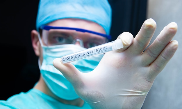 과학자는 바이러스 코로나바이러스가 있는 시험관을 손에 들고 있다