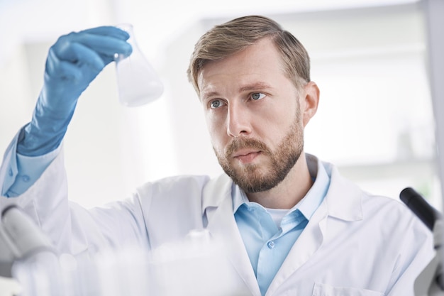 Scientist is carefully looking at the liquid in the test tube