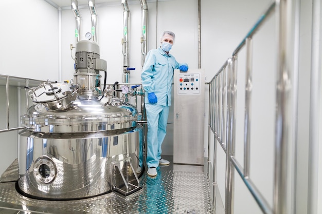 Scientist is standing near big chromed tank